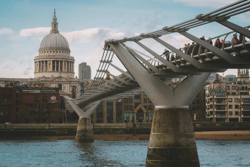 London's Millennium Bridge crossing the River Thames with pedestrians, with the dome of St Paul's Cathedral behind it