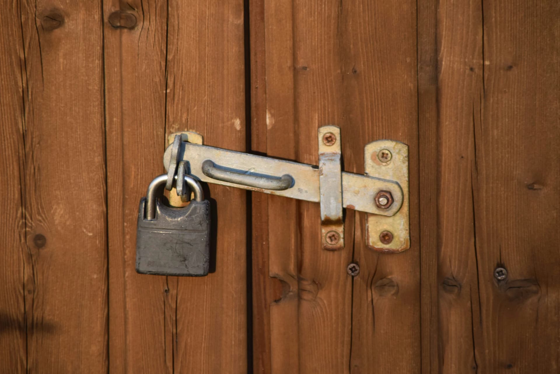 Padlock securing a metal hasp latch on a weathered wooden door